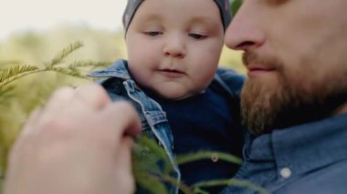 Bir babanın bebeğini kucağına aldığı ve parkta sakin bir günün tadını çıkardığı hassas bir an. Ailevi sevgi ve bağları ifade etmek için mükemmel. Peaceful Park 'ta Gülümseyen Bebek Baba