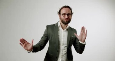 Takım elbiseli bir işadamı elleriyle dur işareti yapıyor. O ciddi ve kendinden emin. Şirket videoları, sunumlar veya reklamlar için mükemmel. Beyaz arkaplan, stüdyo çekimi.