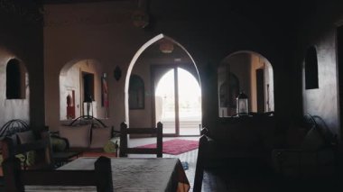 Geleneksel Fas iç mimarisi kemerler, yastıklar ve fayanslı döşemeler. Güneş ışığı kapıdan içeri akarak misafirleri dışarı çıkmaya ve Fas 'ın güzelliğini tatmaya davet ediyor. Konforun karışımı