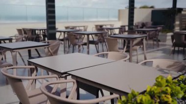 Boş masaları ve misafirleri bekleyen sandalyeleri olan sakin bir avlu. Yemek, rahatlama ya da sosyal toplantılar için ideal. Güneşli bir günde restoranda terasta rahat sandalyeli masalar.