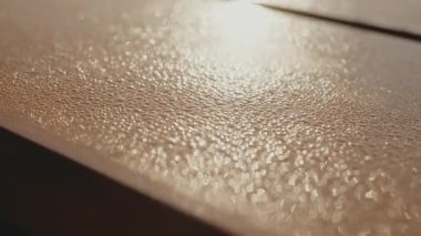 Gri ahşap yüzeyin güzel yakın plan görüntüsü güneş ışığı altında altın bokeh efektini yakalıyor. Tahta yüzeyde Altın Işık Bokeh ile Çiy Damlacıklarının Yakın Çekimi