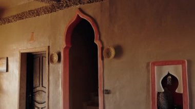 Geleneksel Fas iç tasarımı. Süslü kemer ve kapı aralığı var. Sıcak, dünyevi tonlar ve dekoratif elementler rahat bir atmosfer yaratır. Fas mimarisinin güzelliği