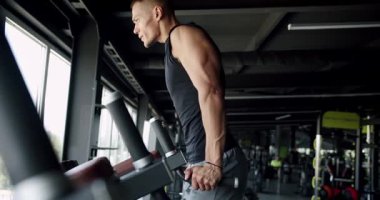 Genç, atletik bir adam yoğun bir şekilde koşu bandında koşuyor, iyi donanımlı, ferah bir spor salonunda, adanmışlık ve fitness hedeflerini vurguluyor. Modern Spor Salonu 'nda Koşu Değirmenine Odaklanan Genç Adam