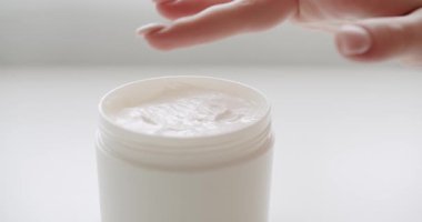 Kadın elleri losyon şişesini alır ve ellerine nemlendirici krem sürer. Cilt masajı için kozmetik ürünleri ve süngerlerle dolu şişeler. Cilt bakımı, hijyen ve sağlıklı yaşam konsepti. Kapat..