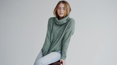 Stüdyo ortamında rahat yeşil bir süveter giyen, gündelik zarafeti somutlaştıran, huzurlu bir yüzü olan çekici genç kadın. Süveter Giyen Genç Kadın Stüdyoda Rahatladı