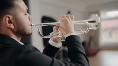Takım elbiseli genç ve yakışıklı bir adam arzu ve ilhamla trompet çalar. Canlı caz konseri. Müzik tutkusu. Genç trompetçinin yakın eli. Müzik odası.