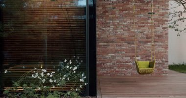 Modern bir evin rahat köşesi, sallanan bir sandalyesi, gür beyaz çiçekleri ve ahşap aksanları var. Huzurlu yaşam tasvir etmek için ideal. Sallanan Rattan Sandalyesi ile Huzur Verandası Ayarlama