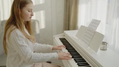 Genç kız evde piyano çalışıyor. Odaklanmış genç, güzel bir kız. Elektrikli piyano çalarak eğleniyor. Müzik dersi veren genç bir müzisyen. Sessiz bir insan piyano çalışır.