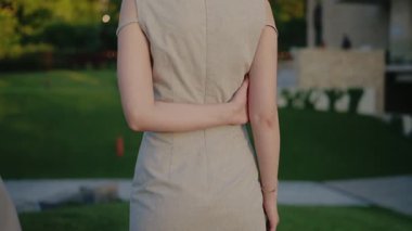 Kaliteli saç stili, kolsuz bir elbise giymiş, açık havada, yeşil arka planda duran zarif bir kadın. Updo Saçlı Zarif Kadın Açık Hava Ayarları