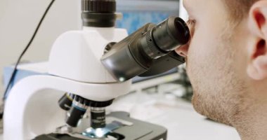 Using a microscope to examine the patients blood health condition. Microscope for blood examination at the clinic. Examining blood under the high-tech microscope equipment. Medical device.