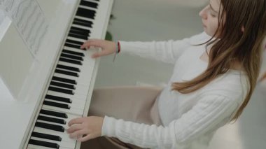 Genç kız evde piyano çalışıyor. Eğitim ve öğrenim geliştirme konsepti. Sessiz bir kişi dairesinde otururken piyano çalışır. Ev müziği stüdyosu kadını. müzik eğitimi.