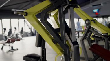 İyi donanımlı kentsel fitness merkezindeki sarı ve siyah bir spor makinesinin yakın çekimi ve arka planda diğer spor aletleri bulanıklaşıyor. Kentsel Spor Merkezi 'nde Modern Spor Malzemeleri