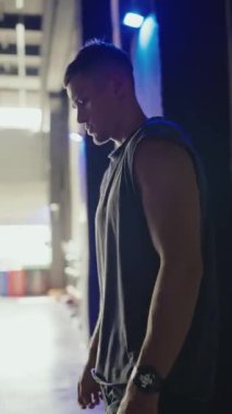 İyi ışıklandırılmış bir spor salonunda antrenman yapmaya hazırlanan bir sporcunun silüeti. Görüntü gücü, bağlılığı ve uygunluğu vurgular. Sporcu Çalışmaya Hazırlanıyor Dikey