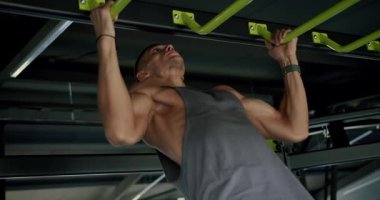 Modern Fitness Spor Salonunda Odaklanan Adam Zorlu Barfiksler Gösteriyor. Formda erkek sporcu, iyi donanımlı, çağdaş bir spor salonunda yeşil bir çubukta yoğun barfiks egzersizi yapıyor..
