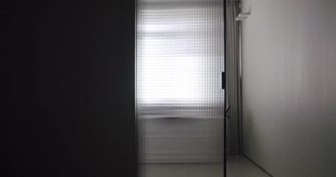 Modern banyoda şeffaf sürgülü kapı açılıyor, beyaz ve gri renkte minimalist küvet. Modern Minimalist beyaz banyo.