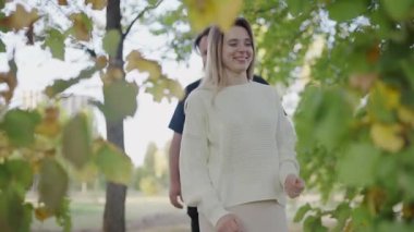 Sevgi dolu bir çift, bereketli ağaçlarla çevrili güneşli bir parkta hassas bir anı paylaşıyor. Görüntü, sevgi, neşe ve yakın bir bağı temsil ediyor. Güneşli bir parkta kucaklaşan Romantik Çift Sevgi ve Sevgi