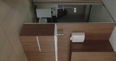 Pahalı ahşap bölmeleri ve parlak ışık altında modern beyaz ofis mobilyalarını gösteren şık bir ofis köşesi manzarası. Modern Ofis Köşesi. Dikey video.