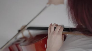 Klasik müzik yaylı klasik müzik enstrümanları, kadın çellocu solo parça çalışıyor. Keman çellosunun yakın görüntüsü ve müzisyenin elleri, bir kadın çello çalıyor..