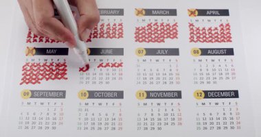 Bir el işaretinin yakın çekimi kırmızı bir kalemle takvimin tarihini gösteriyor. Zaman yönetimi, planlama ve organizasyon kavramı. El İşaretleme Takvimi Zaman Yönetimi ve Planlaması İçin Kırmızı Kalemle Tarihler