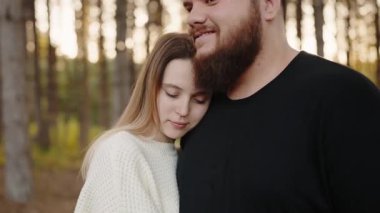 Sevgi dolu bir çift, altın sonbahar ormanıyla çevrili bir şekilde sıkıca sarılır ve yakınlık ve şefkat anlarını paylaşır. Sakin bir sonbahar ormanında kucaklaşan romantik çift.