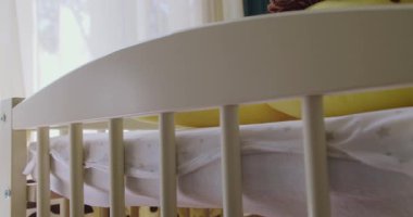 Çocuk odasında koruma sınırları olan ahşap bir beşik. Yumuşak oyuncakları ve yatağı olan modern bir bebek yatağı. Bebek odasındaki bebek yatağında uzanan yumuşak oyuncakların yakın çekimi. Yeni doğan için hazırlık odası.