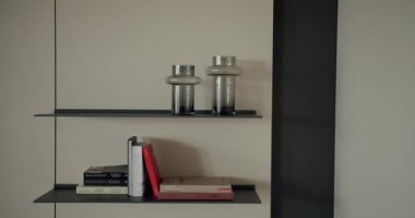Kitaplı modern minimalist raflar, dekoratif cam nesneler, ve parlak bir iç tasarım. İnce ve şık bir ortam. Kitaplar ve Dekoratif Nesnelerle Minimalist Ev Tasarımı