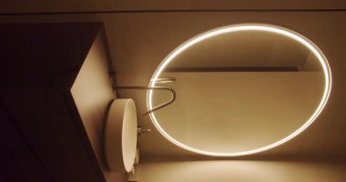 Yuvarlak ışıklı bir ayna ve tezgah lavabosu olan çağdaş bir banyo. Sadelik ve işlevselliği vurgulayan zarif ve modern iç dekorasyon. Modern Banyo Lavabosu Yuvarlak Dikey