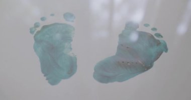 Beyaz arka plan kağıdındaki bebek ayaklarının yeşil izleri. Gri yüzeyde yeşil boyayla ustalıkla işlenmiş insan ayak izleri. Sanatsal yaratıcı ifade. Bebek ayağı..