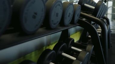 Spor salonundaki dambılların yakın çekim görüntüsü, aktif bir yaşam tarzını yansıtan güncel bir düzenle spor ve egzersiz odaklı. Modern Spor Salonu Yaşam Tarzında Dambıl Rafı
