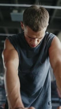 Kendine güvenen bir gencin spor salonundaki portresi. Kararlılık ve odaklanmayı yansıtıyor. Fitness, güç ve motivasyon ile ilgili kavramlar için uygun. Dikey