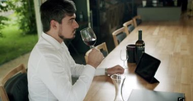 Şarap yapma konsepti. Şarap üreticisi şarap tadıyor. Camın dönüşü şarabın yüzeyini dalgalandırıyor ve uzun cam duvarlar boyunca uzanıyor. Sommelier şarap kadehini sallıyor ve tadına bakıyor.