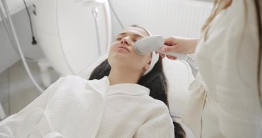 Profesyonel bir kozmetik uzmanı kadın hastalarla güzellik salonunda yüz işlemleri yapar. Kozmetik yenilikleri. Modern teknoloji. Profesyonel bir güzellik stüdyosunda LPG deri masajı..