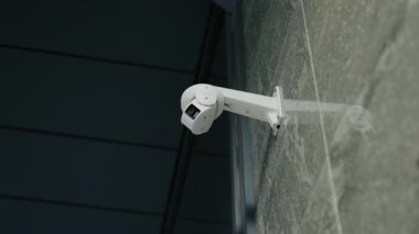 Modern Güvenlik Kamerası. Mermer bir duvara bağlı beyaz güvenlik kamerası. Kamera hafifçe aşağıya bakıyor. Modern bina güvenliği. Gözetleme, mahremiyet, CCTV.