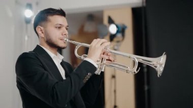 Modern bir stüdyoda trompet çalan bir erkek caz şarkıcısı. Canlı caz konseri. Müzik tutkusu. Genç trompetçinin yakın eli. Müzik odası.