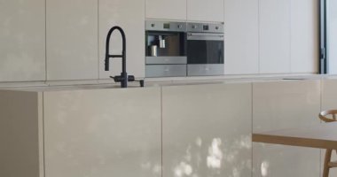 Modern Minimalist Mutfak Tasarımı. Şık ve çağdaş ev vitrinleri, zarif siyah bir musluk, dahili fırın ve kahve makinesi..