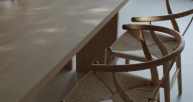 Modern yemek masası ve hafif ahşaptan yapılmış sandalyeler ve dokuma doğal iplik. Güneş ışığı sakin ve davetkar bir atmosfer yaratır. İç tasarım, ev dekorasyonu ve yaşam tarzı içeriği için mükemmel..