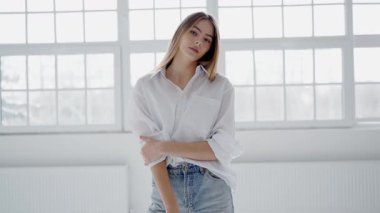 Geniş pencereli, aydınlık bir odada duran beyaz gömlekli, mavi kotlu, kendine güvenen genç bir kadının portresi. Rahat ve düşünceli görünüyor. Sıradan bir zarafeti simgeliyor..