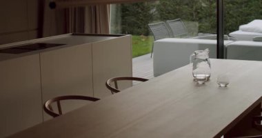 Modern bir evde, parlak, havadar bir mutfak ve yemek alanı. Doğal ışık boşluğu dolduruyor, minimalist tasarımı ve açık hava verandasıyla olan bağlantıyı vurguluyor. Huzurlu atmosfer rahatlamayı davet ediyor.