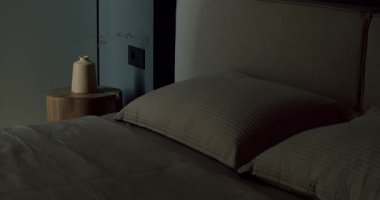 Tarafsız renkler ve minimalist tarzda modern yatak odası iç tasarımı. Karanlık ve kasvetli bir atmosferde yastıkları ve yumuşak yatakları olan rahat bir yatak. Rahatlamak için mükemmel..