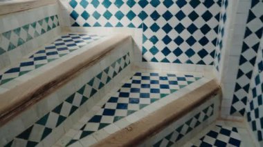 Karmaşık bir şekilde tasarlanmış Fas fayanslarının merdiveni süslemesi. Geometrik desenler ve canlı renkler Fas mimarisinin zengin sanatsal mirası görsel olarak büyüleyici bir sahne yaratıyor..
