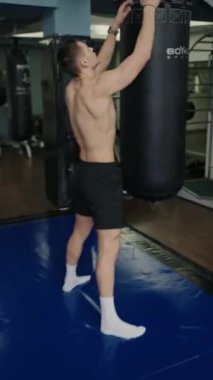 Spor salonunda Odaklanmış Adam Eğitimi, Tıp Topuyla Yoğun Egzersiz. Spor salonunda tıp topu kullanan odaklanmış bir adamın yoğun bir sahnesi. Dikey video.