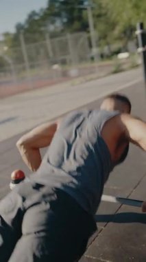 Güçlü bir adam güneşli bir park ortamında açık hava fitness ekipmanlarında şınav çekiyor. Sunlit Park 'ta Şınav çeken Adam Spor Salonu Ekipmanı
