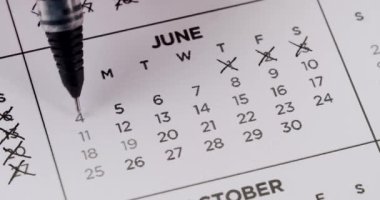 Birisi haziran ayının her gününü basılı takvimden işaretlemek için siyah kalem kullanıyor. Her randevuya birden fazla x koyuyorlar. Zamanın geçişini ya da günleri saymayı simgeliyorlar. Takvimdeki Tarihler