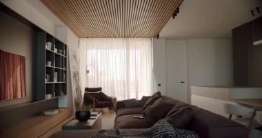 Rahat mobilyalar ve şık dekorlarla modern oturma odası. Perdelerin ardındaki doğal ışık sıcak bir ortam yaratır. Minimalist tasarım nötr renk paleti sofistike bir his veriyor
