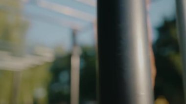 Parkta barfiks çubuğunda egzersiz yapan kaslı bir adam. Dayanıklılık, spor ve açık hava sporlarına odaklan. Parlak gün atletik enerjiyi ve kararlılığı arttırır. Barfiks Çeken Atletik Adam