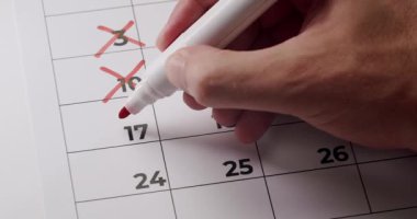 Takvimdeki tarihleri kırmızı kalemle işaretleyen bir el resmi. Zaman yönetimi, zamanlama ve geri sayım kavramı. Takvimdeki Tarihleri Kırmızı İşaretli Kalemle Elle Silme