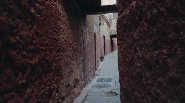 Fas 'ta dar bir sokakta yürüyorum. Duvarlar pürüzlü ve düzensiz, renkler de soluk. Atmosfer sessiz ve huzurlu. Bu video bir macera ve keşif hissi uyandırıyor.,