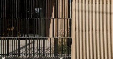 Modern evin dış görünüşü, sürgülü metal bir kapısı ve ahşap bir yüzü var. Modern bir evde şık bir tasarım ve mimari. Güvenli giriş mahremiyet ve ayrıcalık hissine katkı sağlar..