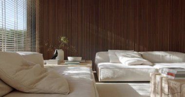 Modern, minimalist iç tasarımı olan parlak, ferah bir oturma odası. Rahat beyaz koltuklar, ahşap duvar panelleri ve şık dekorlar huzurlu bir atmosfer yaratıyor. Rahatlama ya da sessiz yansıma.