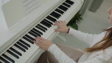 Odaklanmış genç, güzel bir kız. Elektrikli piyano çalarak eğleniyor. Müzik dersi veren genç bir müzisyen. Müzik eğitimi. Eller piyano tuşlarına basıyor. Nota okuyorum. Piyano öğrenme dersleri